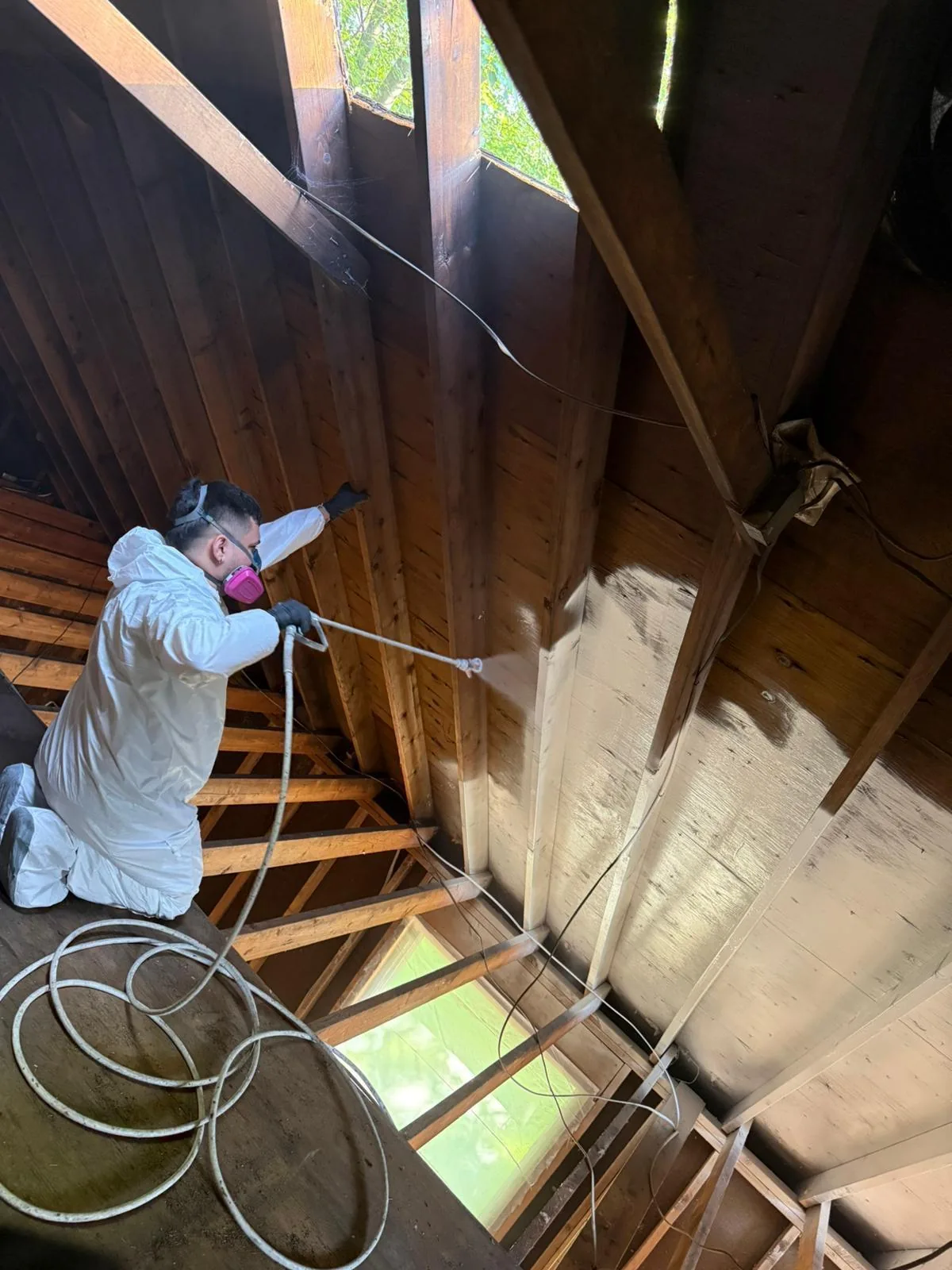 A GRADE technician in protective gear cleaning a fire-damaged attic